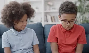 happy girl looking at diffident brother while they both sit on a sofa synthex adobestock 484172833
