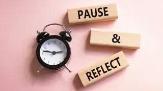 the words pause reflect printed on blocks next to a alarm clock against a pink background natallia adobe stock 1776723426