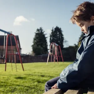 a child looking lonely while sitting on a park bench brian jackson adobe stock 100207516