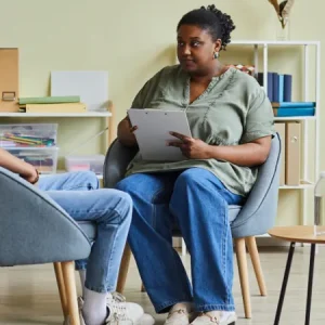 a serious looking social worker speaking to a young man in care seventyfour adobestock 512013243 (1)