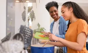 a woman and a girl smiling while cooking together credit adobe stock 631115162
