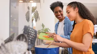 a woman and a girl smiling while cooking together credit adobe stock 631115162