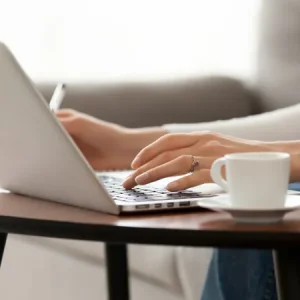 a woman typing on a computer at home fizkes adobe stock 261283789