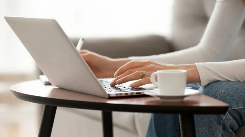 a woman typing on a computer at home fizkes adobe stock 261283789