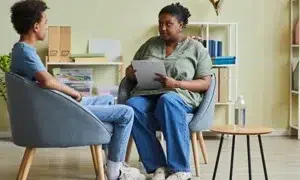 a serious looking social worker speaking to a young man in care seventyfour adobestock 512013243